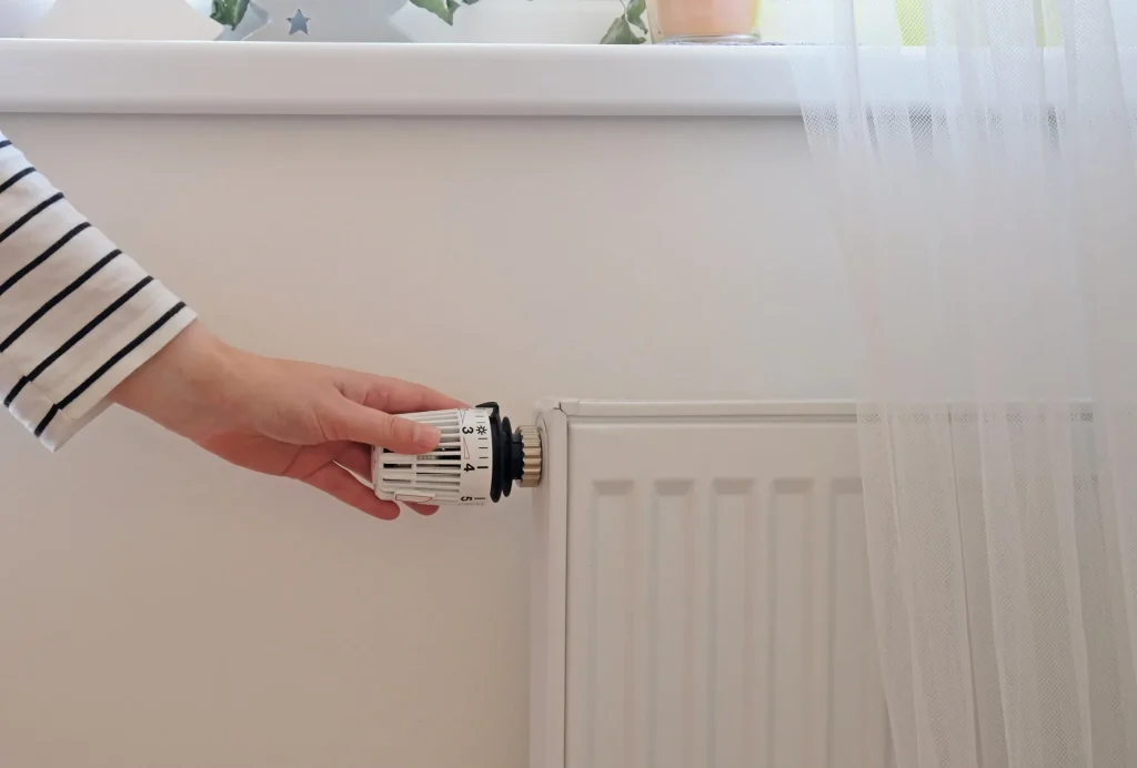 woman regulating heat temperature at home